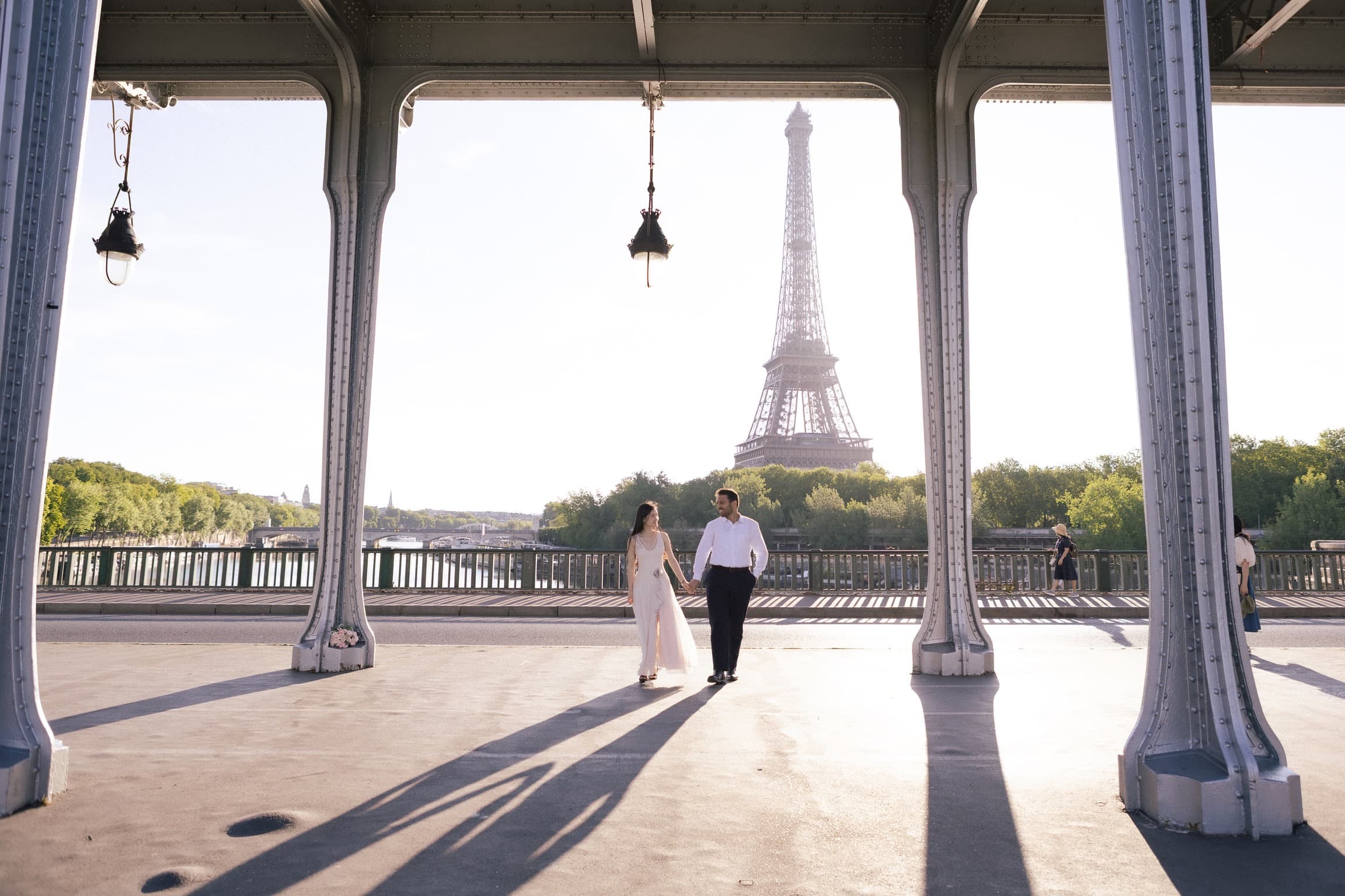 The couple walking together beneath the Paris pavilion with the Eiffel Tower in the distance.